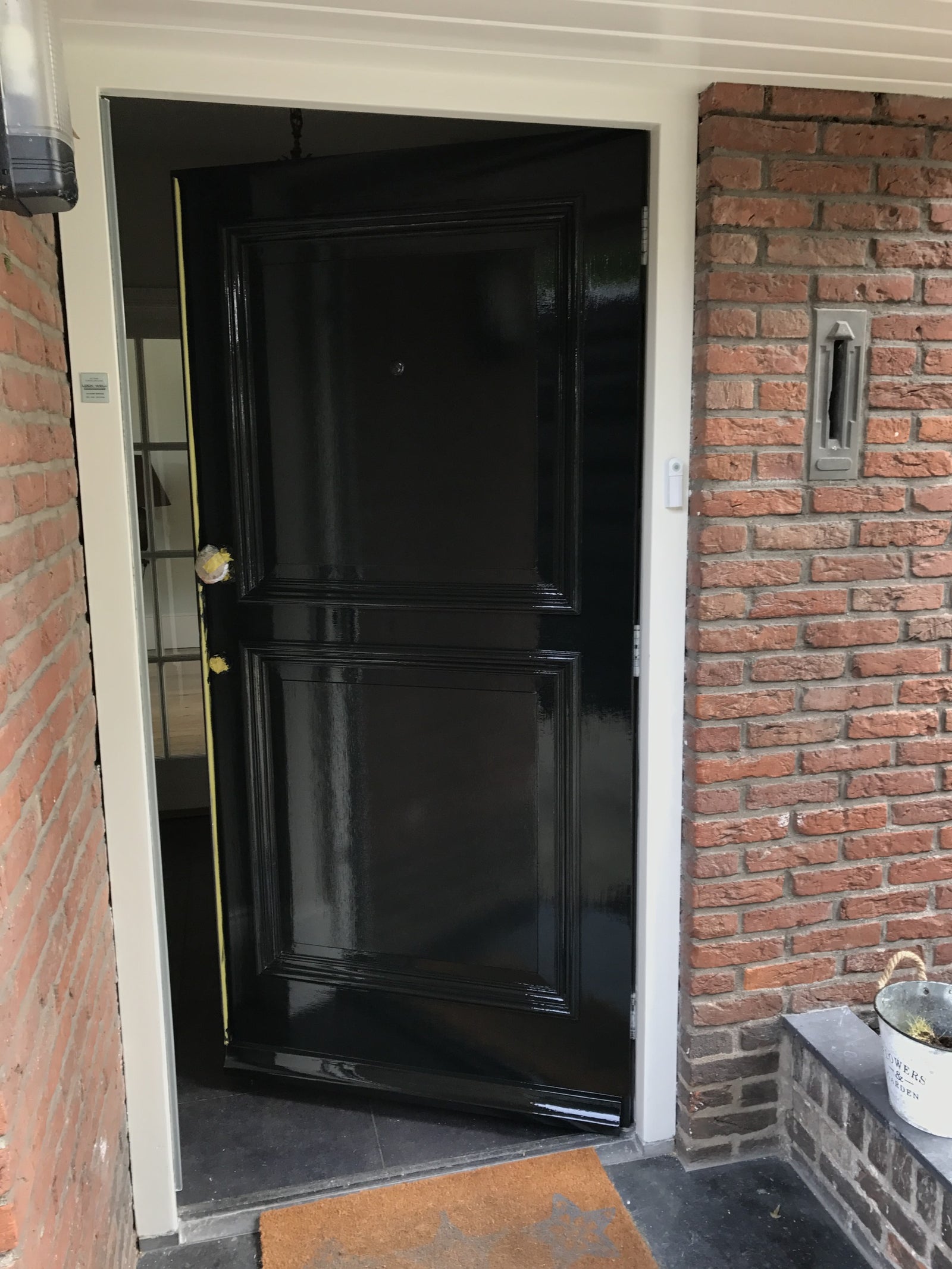Hoogglans zwarte paneeldeur in een bakstenen gevel