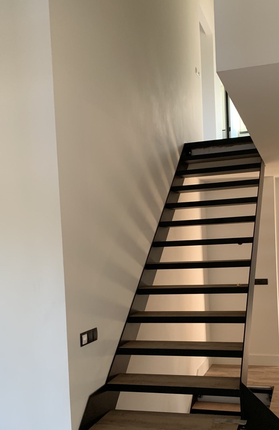 Open stalen trap tegen een witte wand